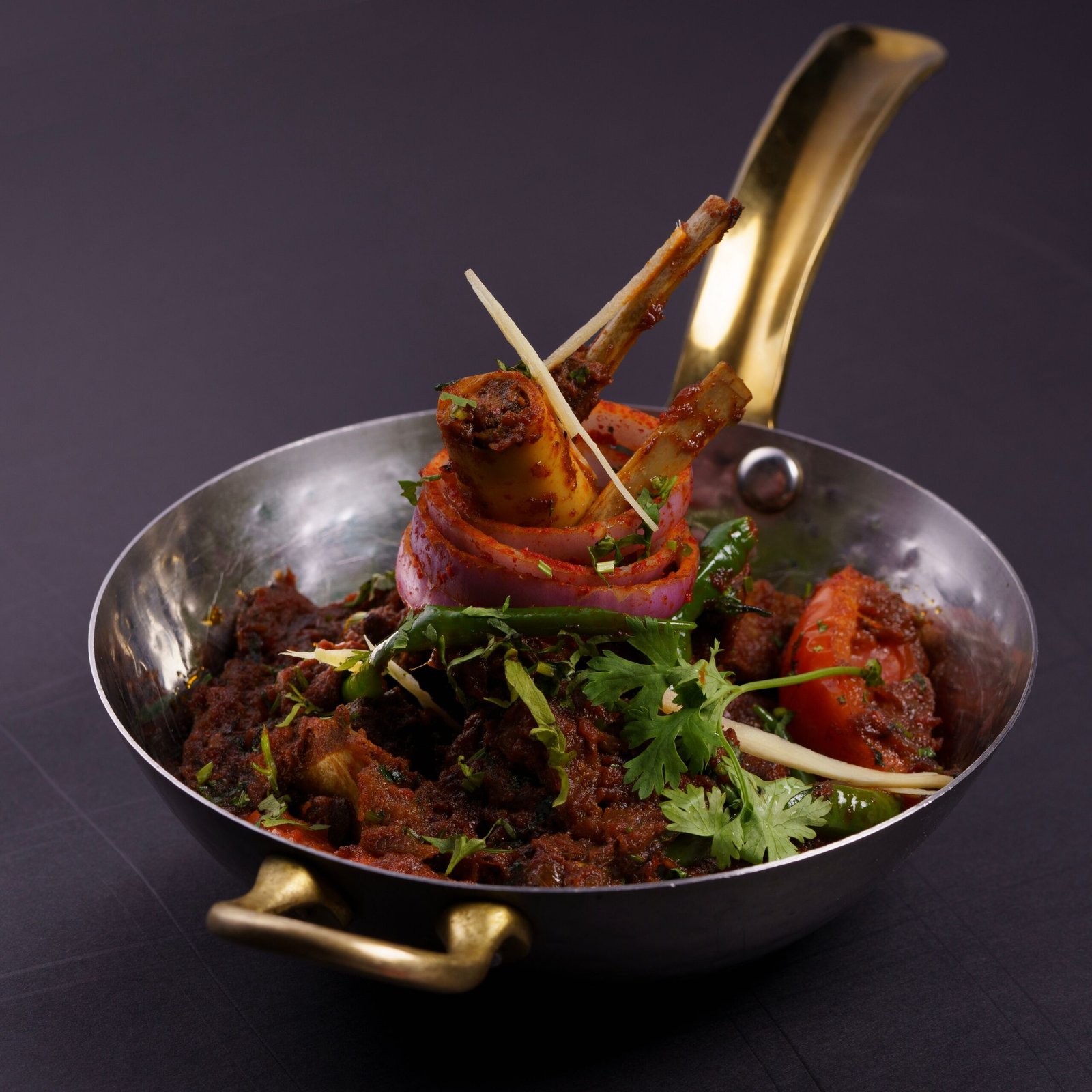 Delicious Indian mutton curry garnished with herbs, served in a rustic pan.