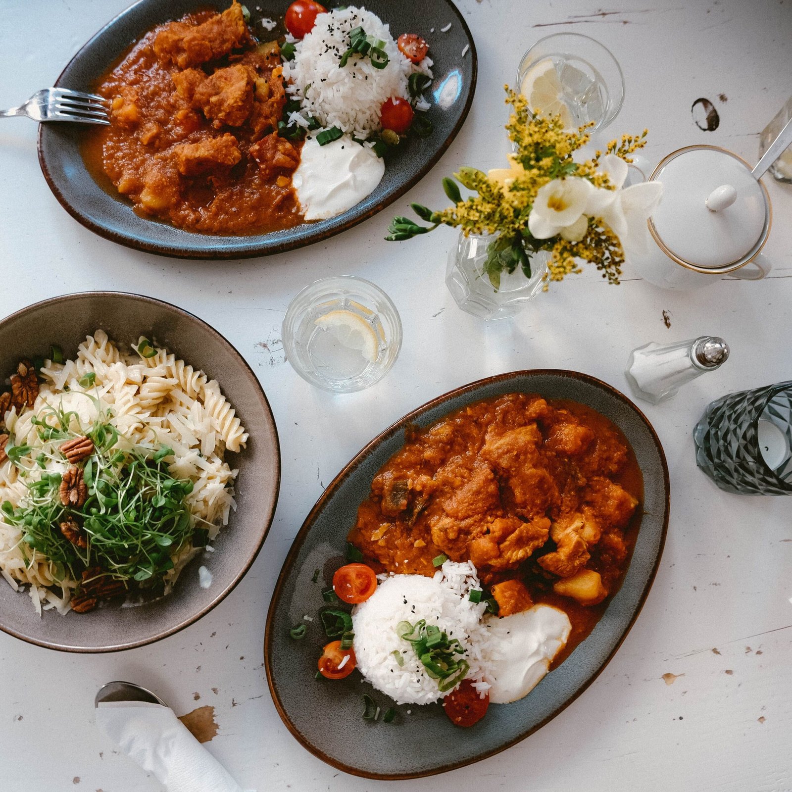An inviting arrangement of Italian pasta and Indian curry dishes on a light surface.